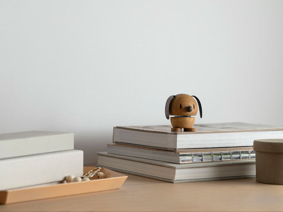 Small wooden dog figurine on a stack of books with a plain background